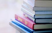 A tall stack of colorful hardcover books on a table indoors, perfect for library-themed concepts.